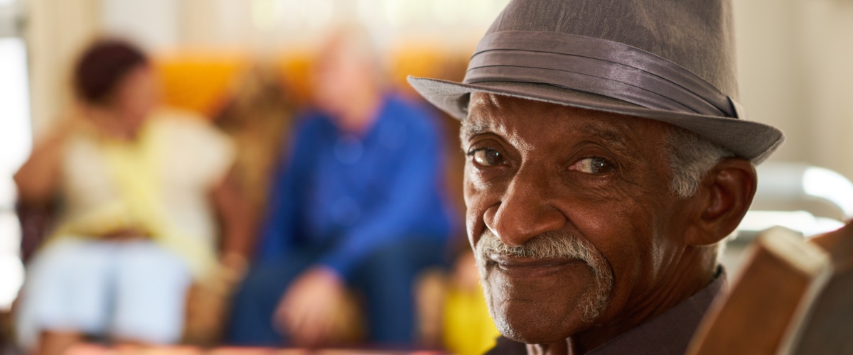 An elderly man sitting down in a chair looking back at the camera