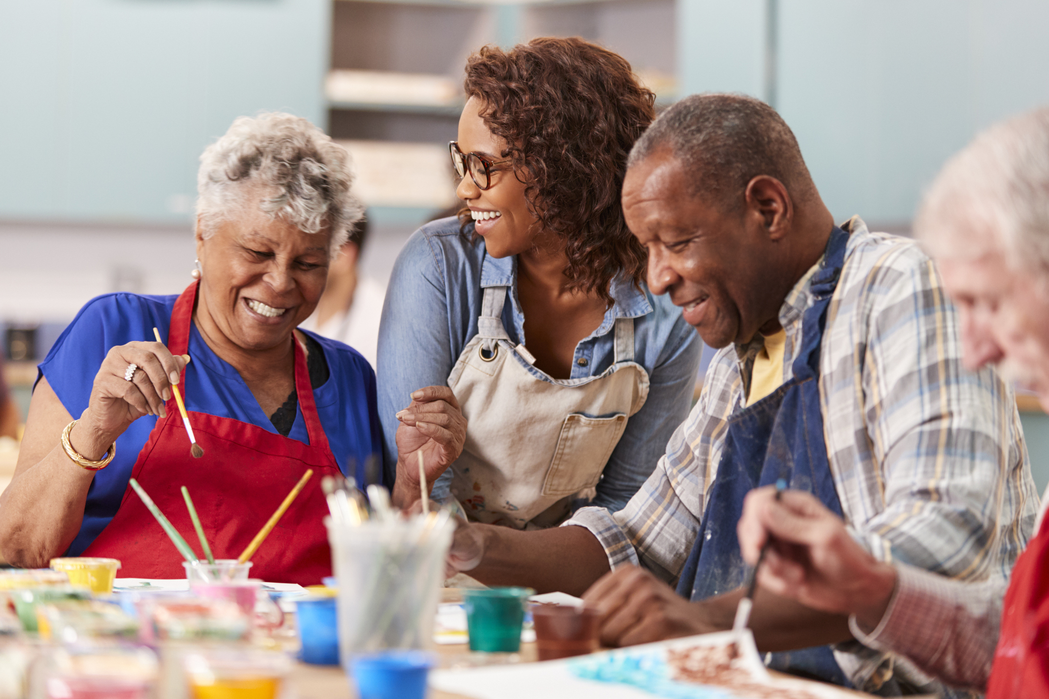 A diverse group of individuals engaged in painting together at a table, showcasing their creativity and artistic collaboration.