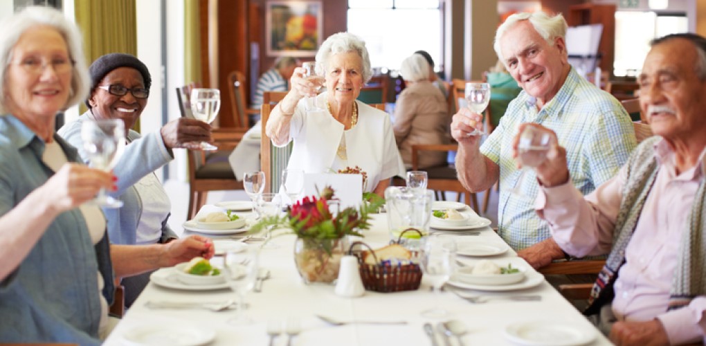 Elderly people eating and talking around a dinner table