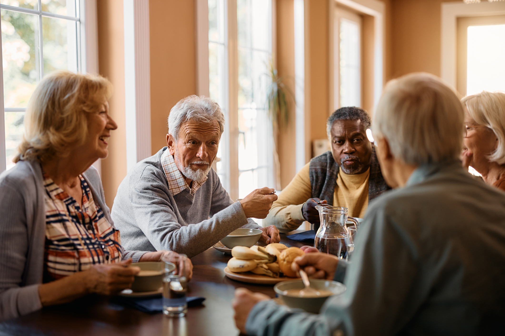 A group of older adults gathered around a table, enjoying a meal together in a warm, inviting setting.