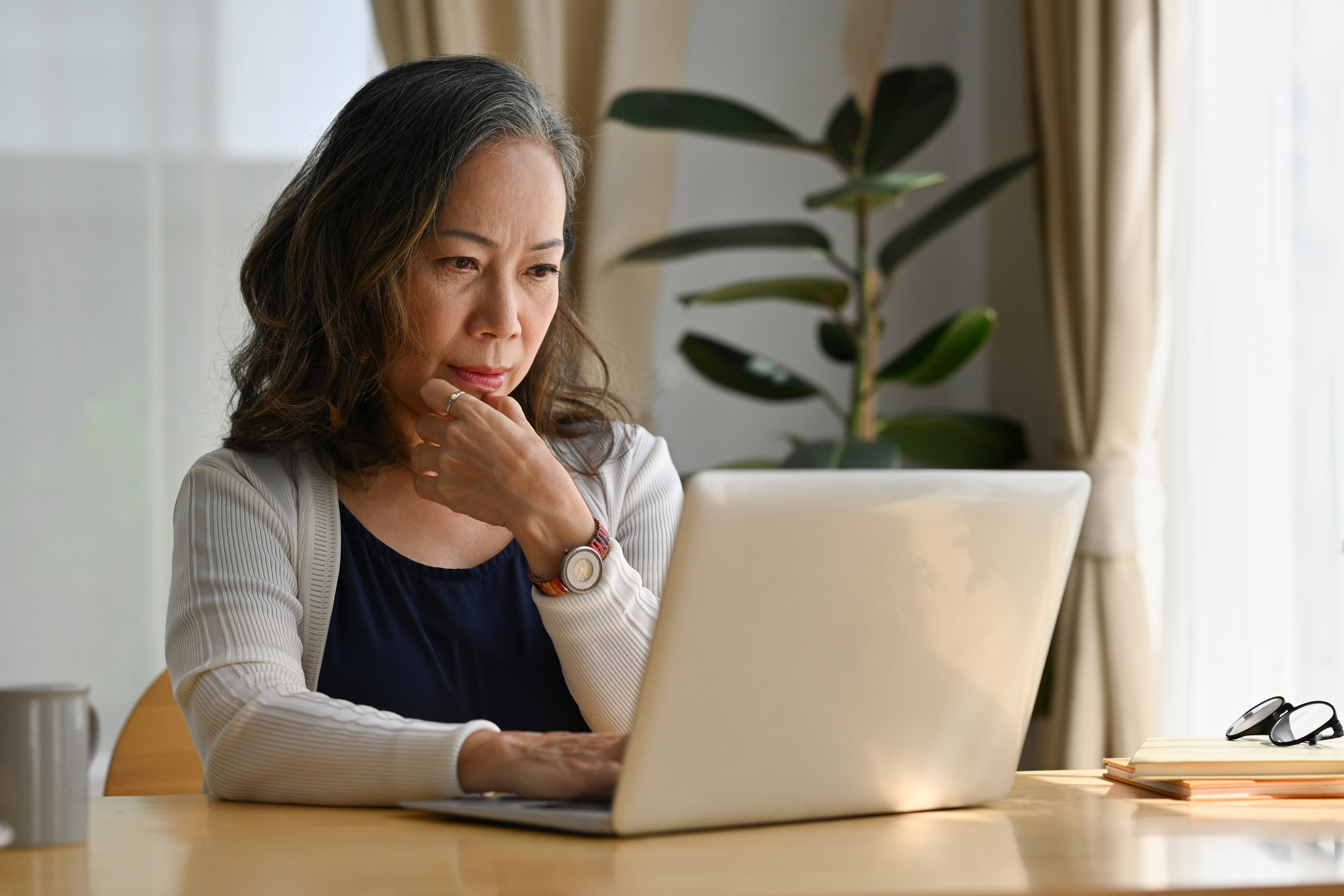 Senior woman sitting on a chair and looking at her laptop.