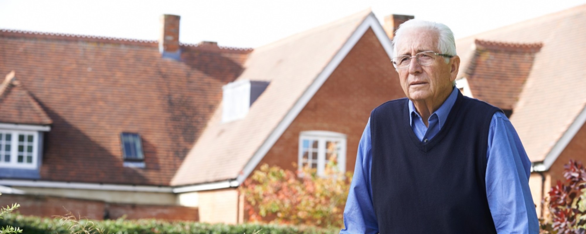 An elderly man in front of his house