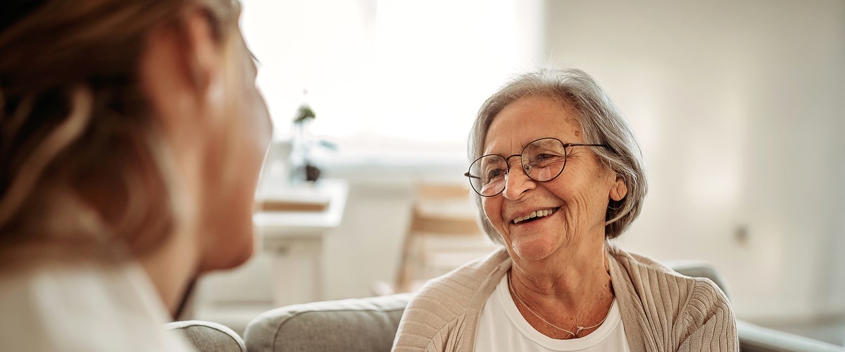 older adult woman smiling and speaking with patient representative