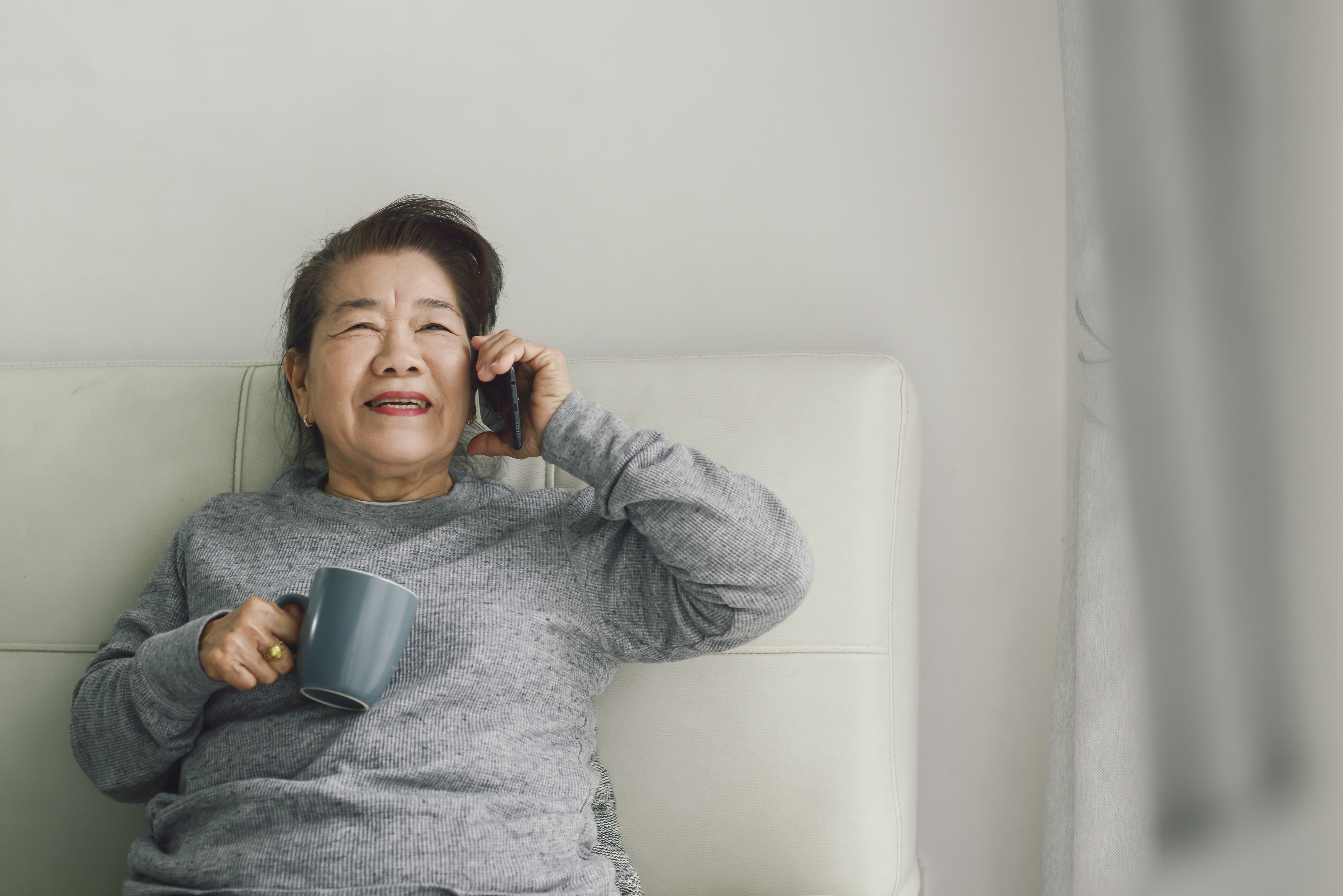 An eldery latino lady is talking happy using a cell phone