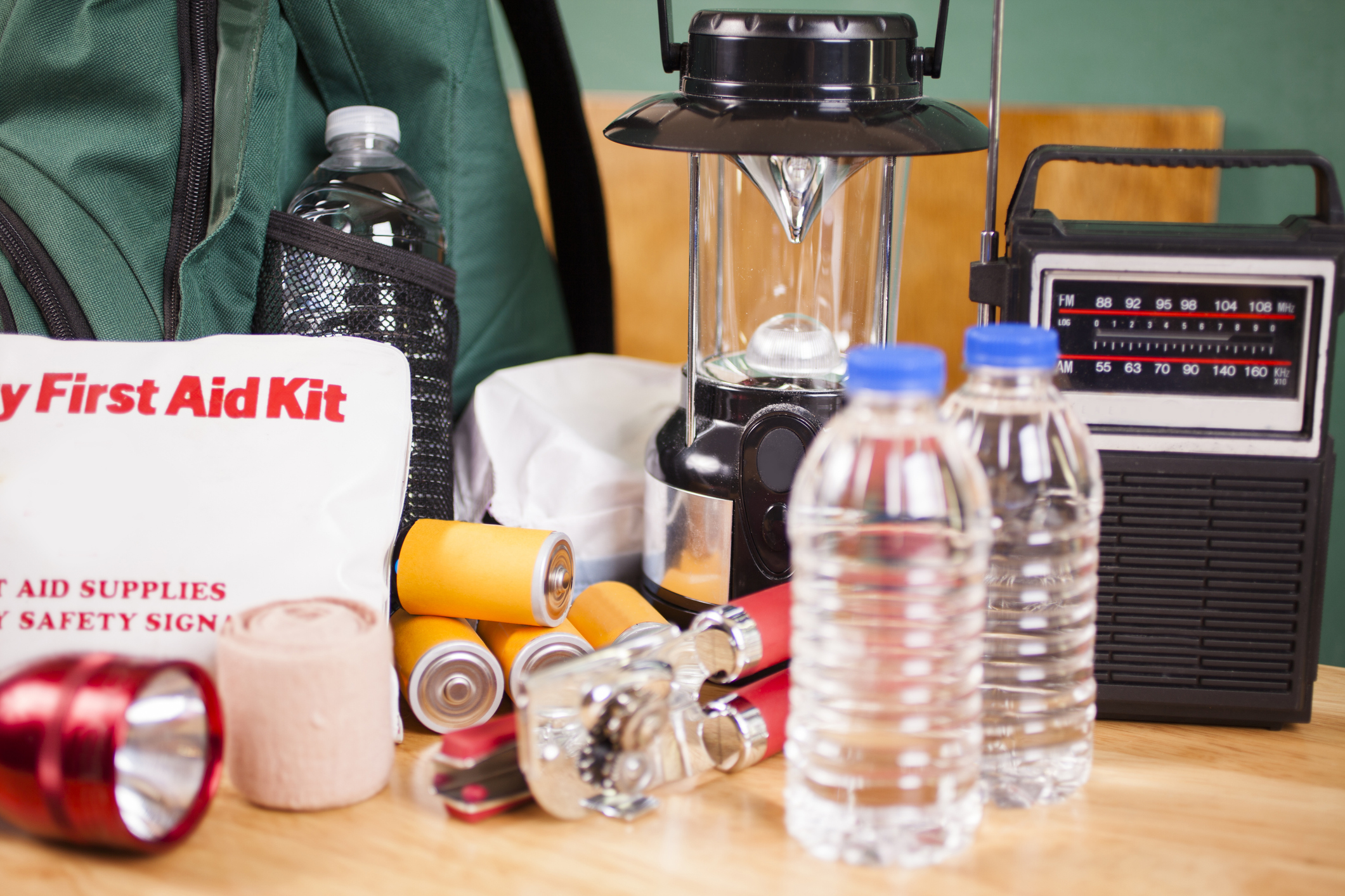 image of emergency supplies including first aid kit, batteries, water bottles, radio, lantern, and backpack