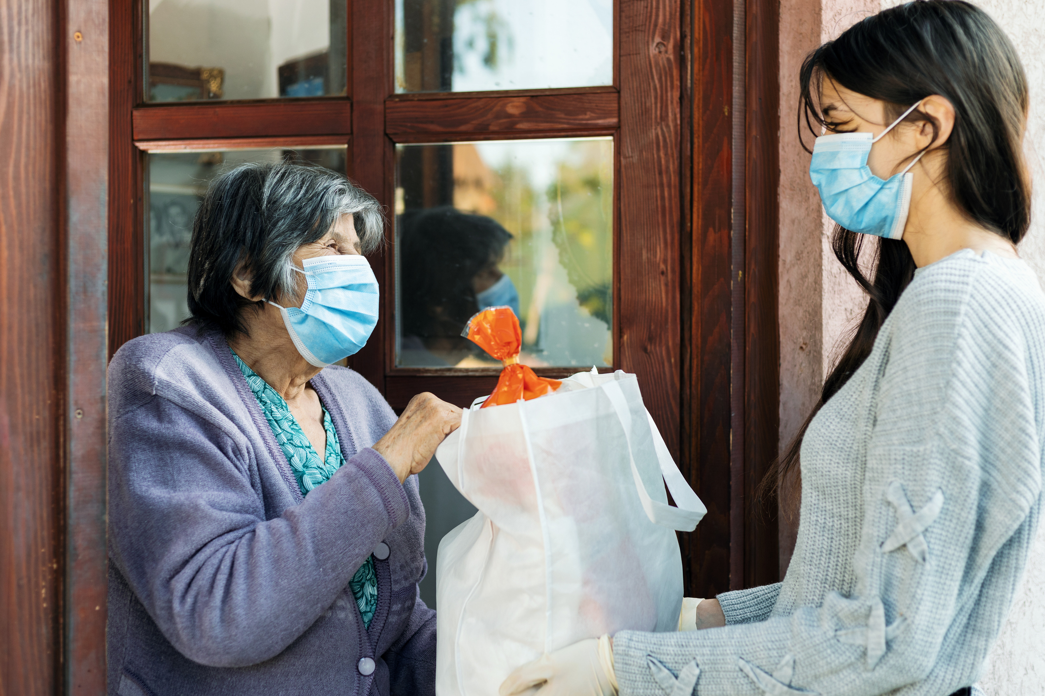 Teenage girl volunteer delivering groceries to a older woman