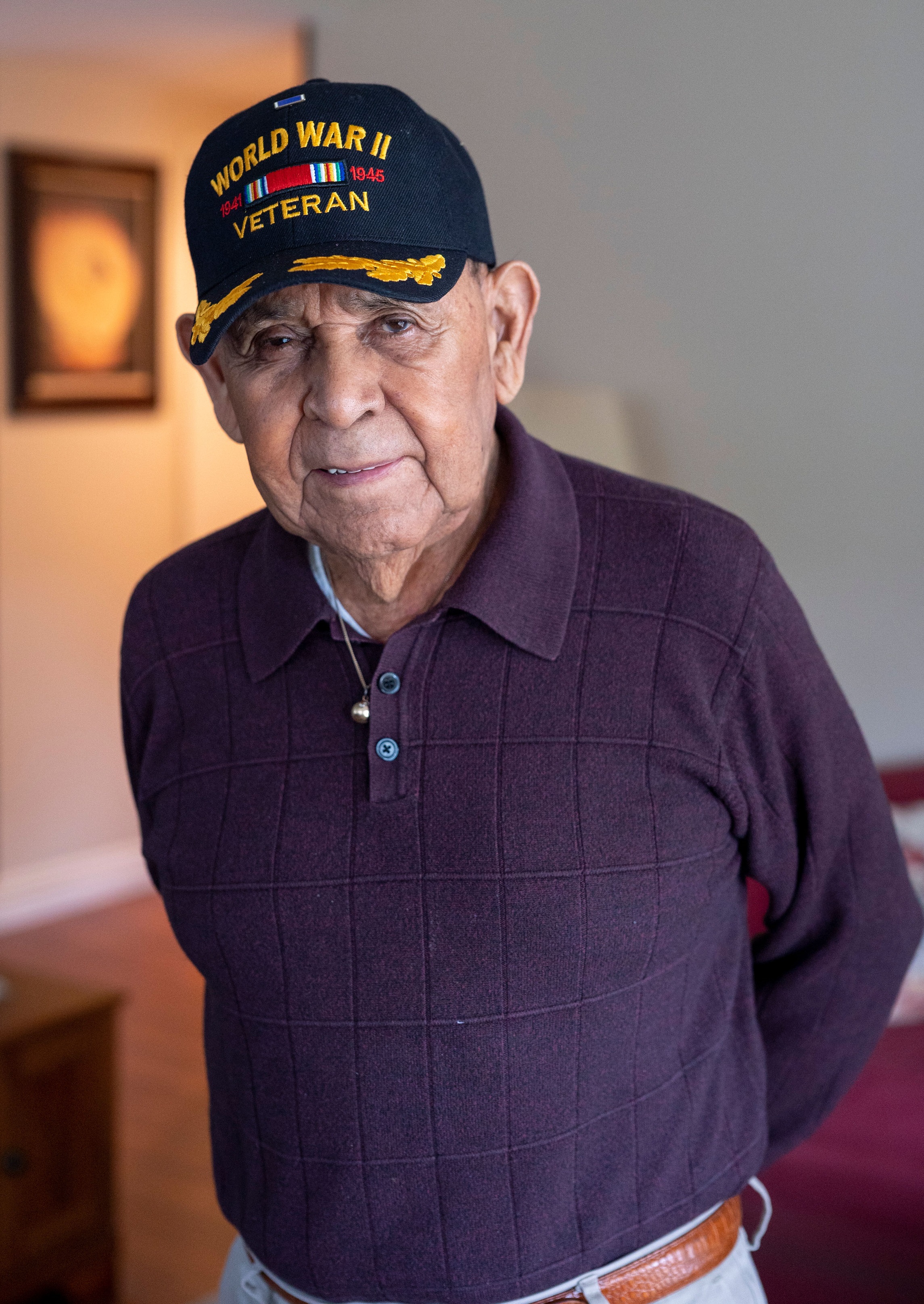 A World War II veteran wearing a purple shirt and a hat.