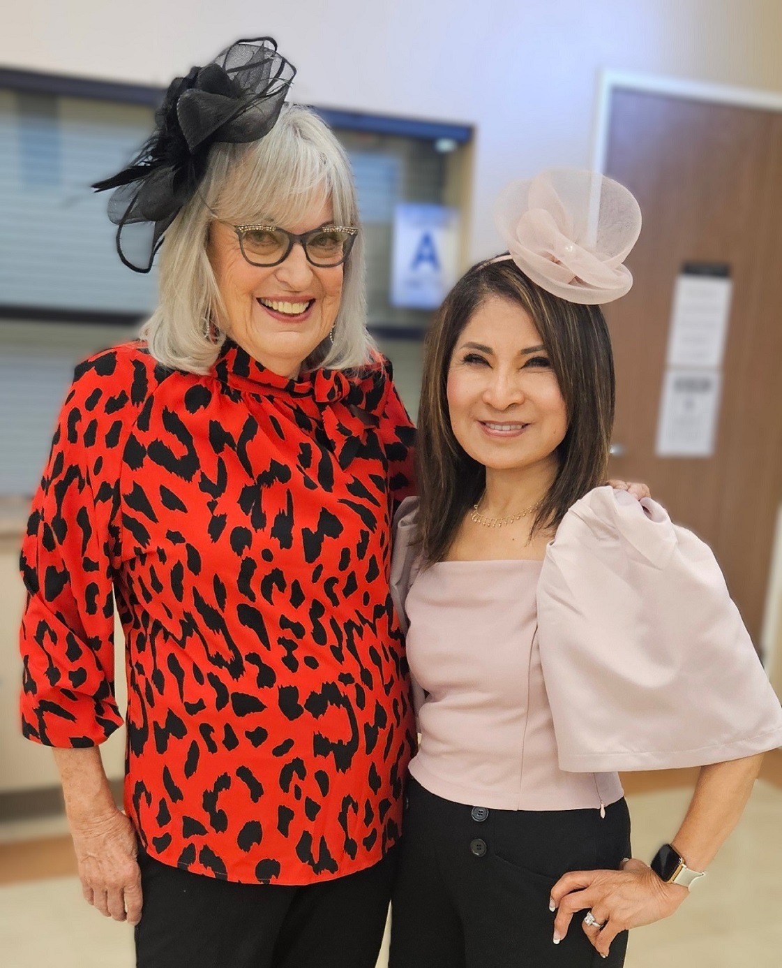Catherine and Amor in matching black and red attire stand next to each other.