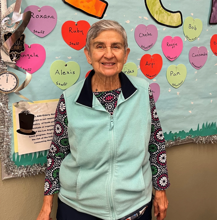 Mrs. Cecilia Greenwalt stands beside a bulletin board covered with flyers and announcements, engaging with the displayed content.
