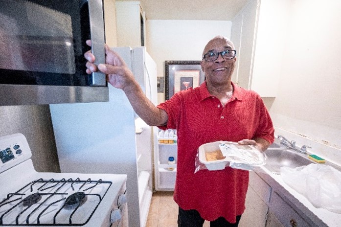Rober tstands holding a tray of heated up food