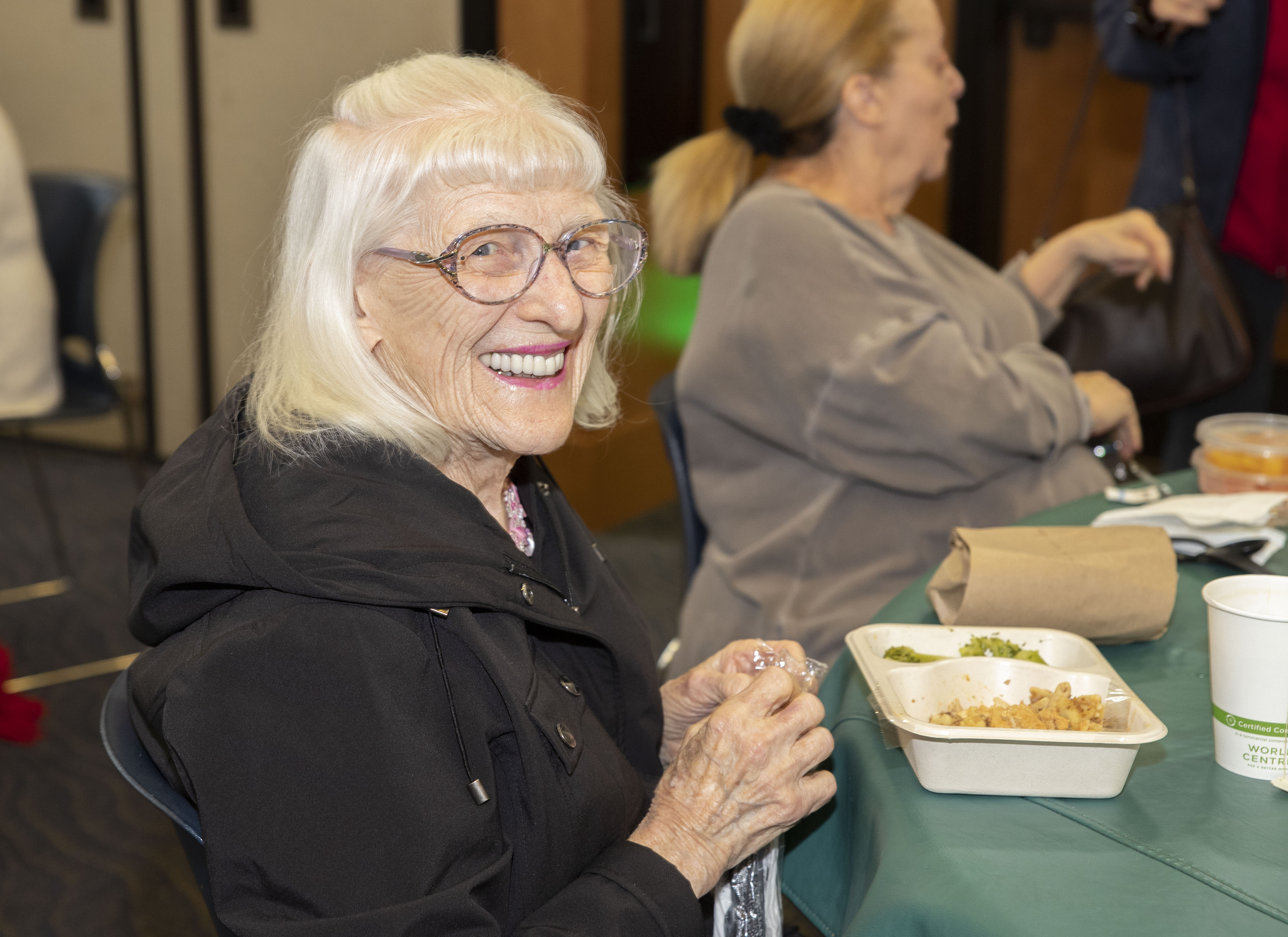 Woman with short white hair in black jacket smiling