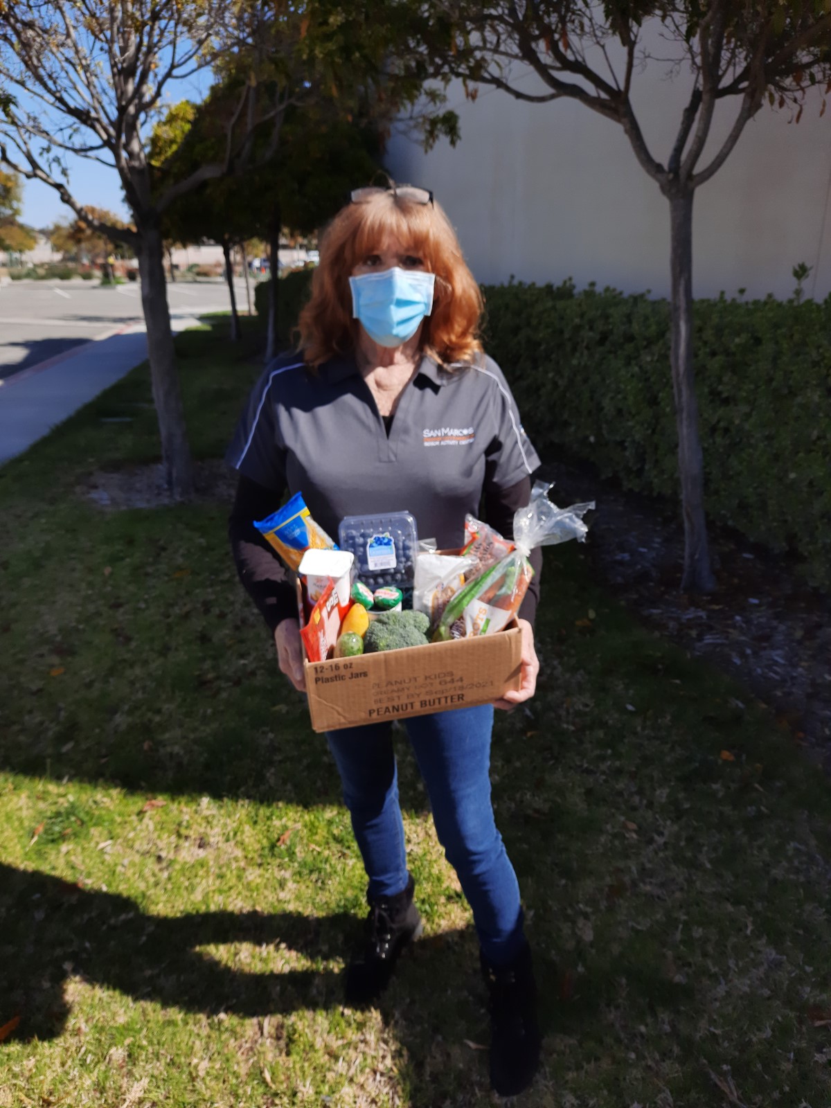 Older adult woman holding a box of fresh fruit and vegetables.